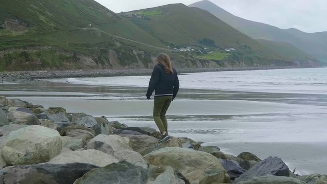 Girl climbs over the rocks of the Irish coast