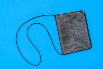Leather black women bag on blue background. The view from the top. Flat lay.