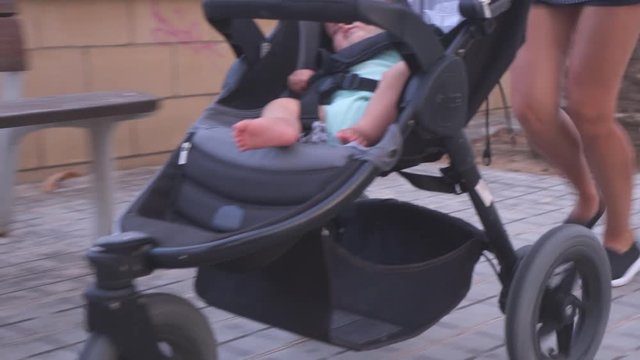 Woman pushing baby buggy while exercising outdoors