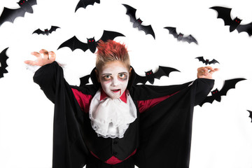 Scary Halloween vampire boy dressed up for spooky halloween party and holding an orange halloween pumpkin jack o lantern