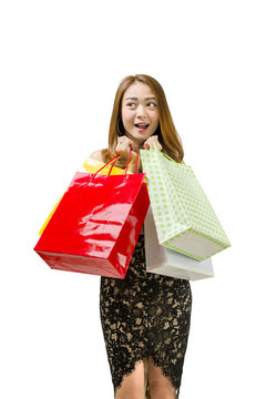 Excited asian woman with colored shopping bags standing