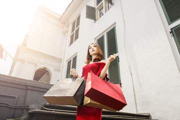 Young asian woman standing with colored shopping bags