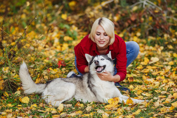 Naklejka na ściany i meble Beautiful caucasian girl plays with husky dog in autumn forest