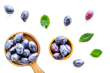 Blue plum for dessert. Purple plum and leaves pattern on white background top view