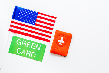 Fototapeta premium United States of America permanent resident cards. Immigration concept. Text green card near passport cover and US flag top view on white background copy space