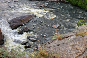 the rapids on the river in the centre of the stones that encircles the water fast over the forest mountain river