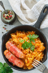 Stewed cabbage with carrots, onions and tomatoes and sausages in bacon with parsley and spices in a cast iron pan. Bigos. Delicious lunch