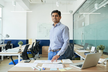 Portrait of happy Indian UX designer standing in modern office