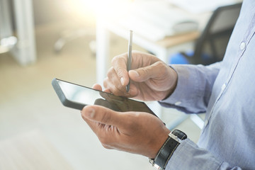 Hands of businessman using stylus when using smartphone