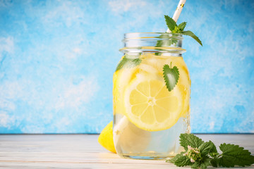 Coctail jar of lemonade and mint leaves on wooden table blue background