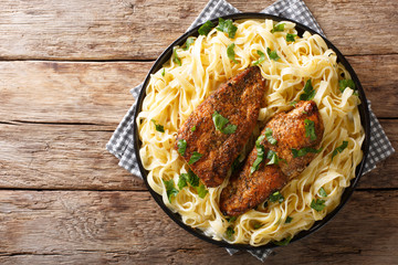Cooker Chicken Lazone is seasoned breast fried in butter, pressure cooked until tender, served over pasta closeup. horizontal top view
