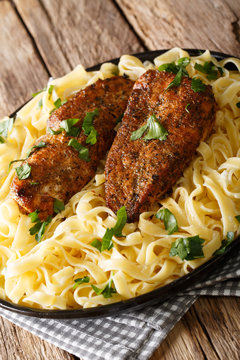 American food: chicken lazone breast fried with spices and fetuchine pasta in a creamy sauce closeup. vertical