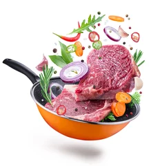 Crédence de cuisine en verre imprimé Viande Flying meat steaks and spices over a frying pan. File contains clipping path. Isolated on a white background.