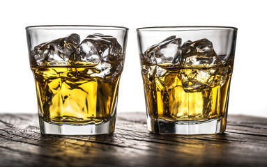 Whiskey glasses or glasses of whiskey with ice cubes on the wooden background.