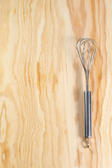 Single silver whisk on a wooden table 