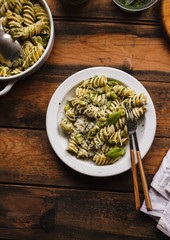 Fussillioni pasta green pesto plate on old wooden board