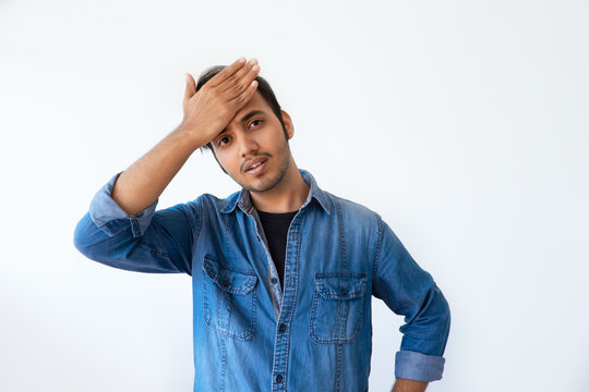 Annoyed Indian man slapping forehead and blaming himself. Regretful handsome dark haired man wearing denim shirt gesturing and looking at camera. Forgetfulness concept.