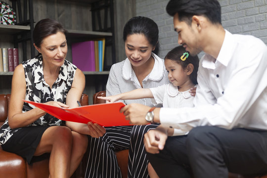 Happy young Asian family talking with psychologist or family counselor In life insurance coverage or real-estate agent house investment or bank worker offers loan or financial advisor with clients.