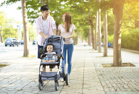 happy family with baby carriage walking in the park