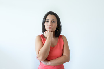 Fototapeta premium Pensive attractive Caucasian woman with pressed lips holding chin. Pretty middle aged woman in pink dress thinking about new solving problem. Business difficulties concept.