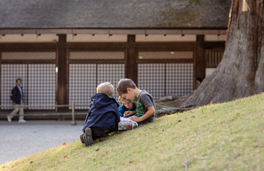 Fototapeta na wymiar Three boys reading the tourist guide book in front of a japanese zen temple