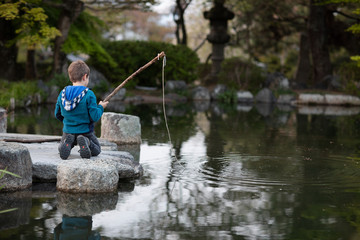 Boy fishing in a pond of a japanese garden