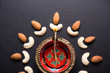 Diwali diya concept using Cachew/Kaju and Almond/Badam aoing with oil lamp and flowers