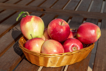 red apples in a basket on a wooden table