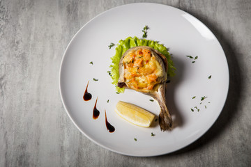 top view on baked trout with stuffing, salad, lemon and sauce