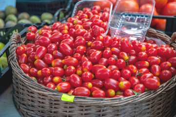 Red ripe cherry tomatoes sell at the farmer's market on a Sunny autumn day in a wicker basket