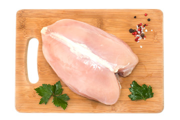 Raw chicken Breasts and spices on wood chopping Board isolated on white