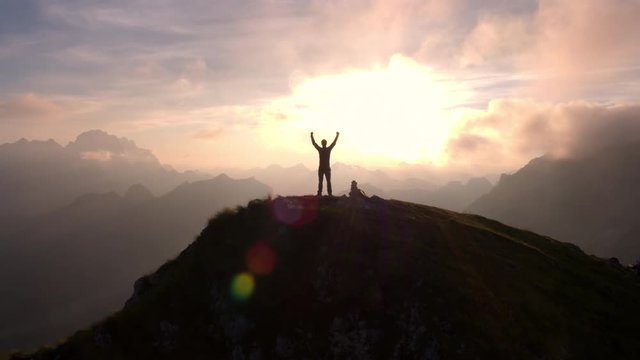 Aerial - Moving above silhouette of a man standing on top of the mountain