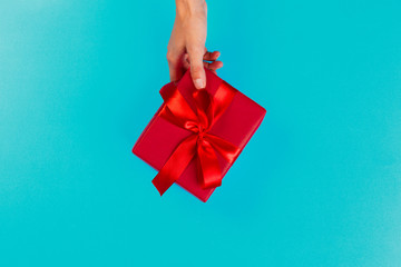 Woman holding gift box on color background
