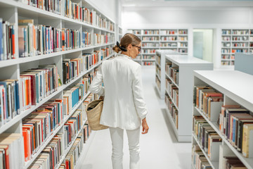 Woman in the library - obrazy, fototapety, plakaty