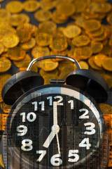 Double exposure of alarm clock and coins stacks with city background and finance graph, time for savings money concept, banking and business concept