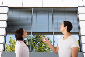 Couple Adjusting Temperature Of Air Conditioner