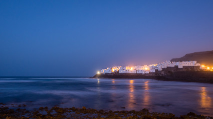 beautiful white village on a rock by the sea at blue hour