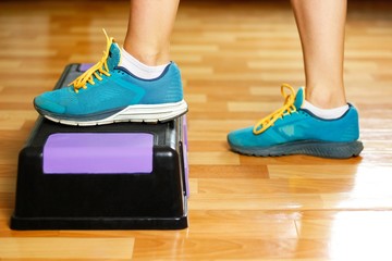 The girl in sneakers is engaged on the step-platform for fitness. Feet on the step for sports. Close up