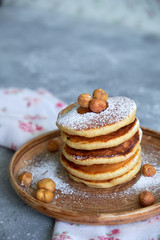 pancakes sprinkled with nuts hazelnuts on a plate with a napkin on a concrete background