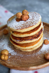pancakes sprinkled with nuts hazelnuts on a plate with a napkin on a concrete background