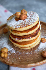 pancakes sprinkled with nuts hazelnuts on a plate with a napkin on a concrete background