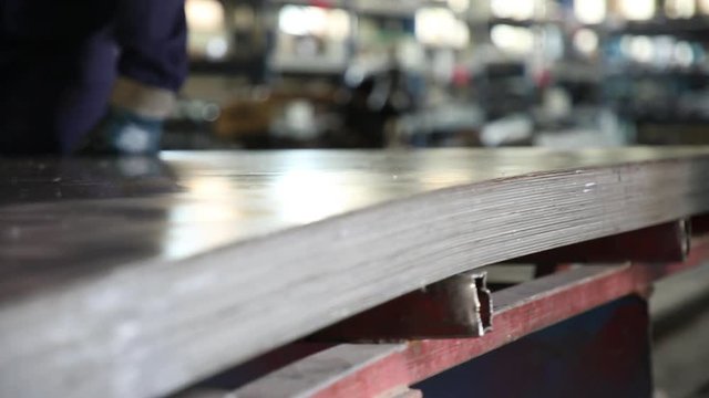 Metal sheets on the shipping cart. The cart moves on rails in the shop.  Production room. Employees in overalls push the shipping cart. On the cart sheets of metal are put. Sheets are taken a close-up