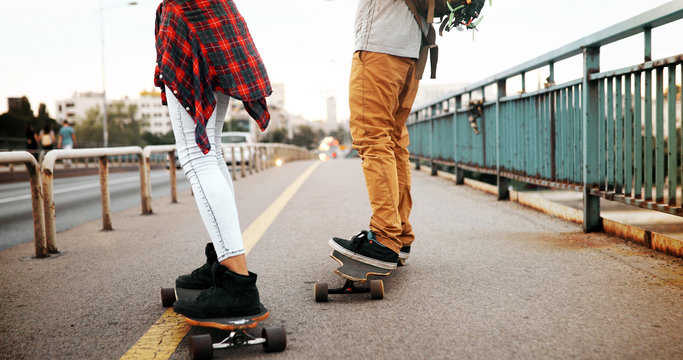 Picture of young attractive couple carrying skateboards