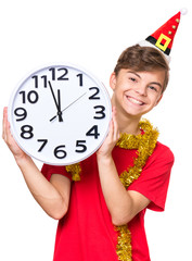 Portrait of smiling teen boy with Christmas hat. Teenager wearing red t-shirt holding big clock. Holiday concept - happy cute child isolated on white background.