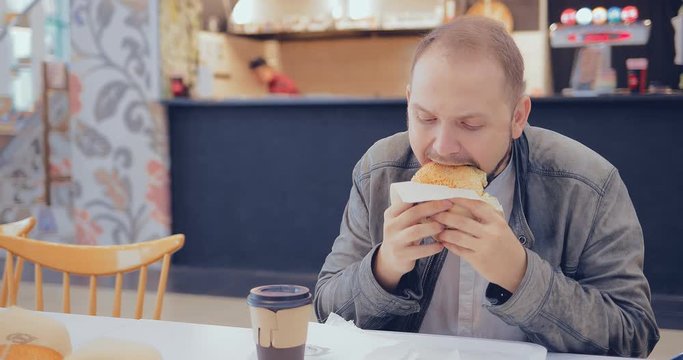 Man eating a burger in a fast food cafe