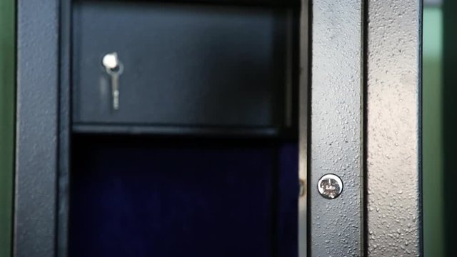 Open safe. Open safe of black color. Internal sections are visible. Inside one more section which is protected by a door. The key is inserted into a keyhole. Shooting through refocus.