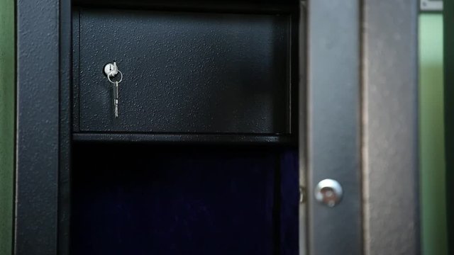 Open safe. Open safe of black color. Internal sections are visible. Inside one more section which is protected by a door. The key is inserted into a keyhole. Shooting through refocus.