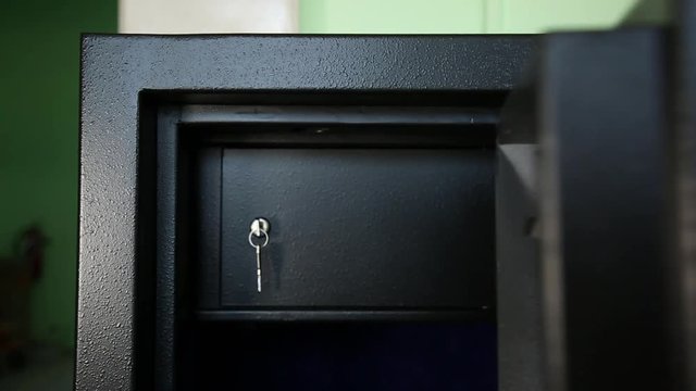 Opening of a door of safe. Opening of an external door of the safe. Behind her it is visible to one more section. The section is protected by one more door. The key is inserted into her..
