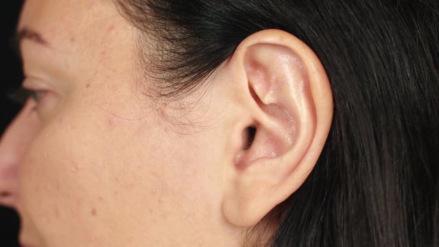 Female left ear close up. Ear of adult brunette woman. Parts of face and body