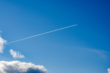 Large passenger supersonic plane flying high in clear blue sky, leaving long white trail